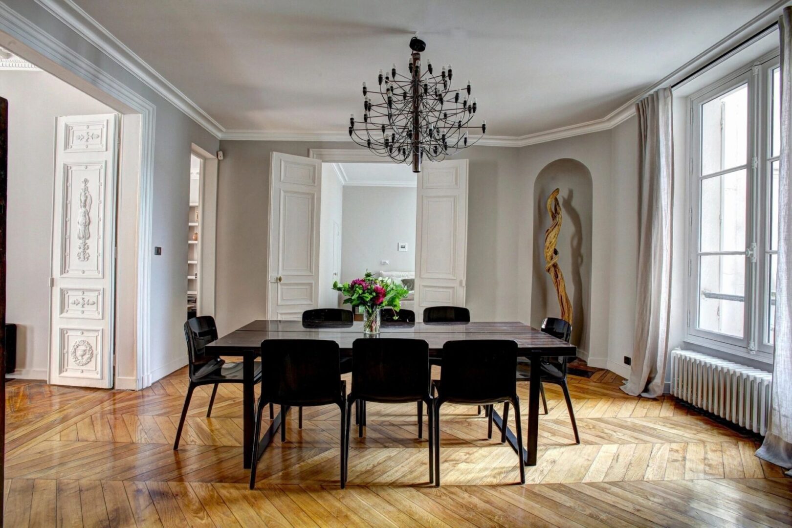 A dining room table with black chairs and chandelier.