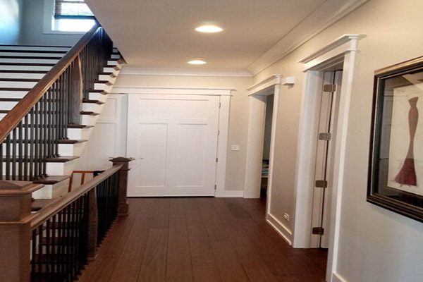 A hallway with stairs and a door way.