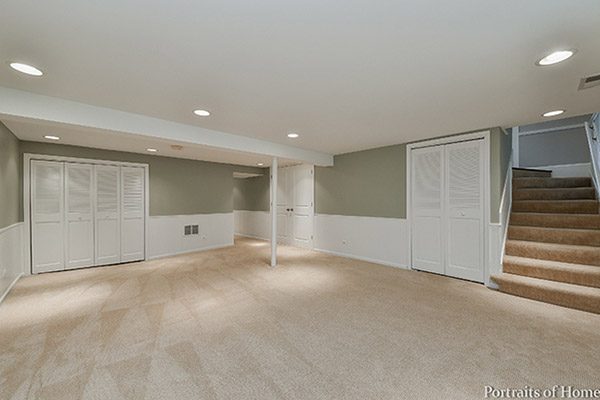 A large empty room with two doors and a white wall.