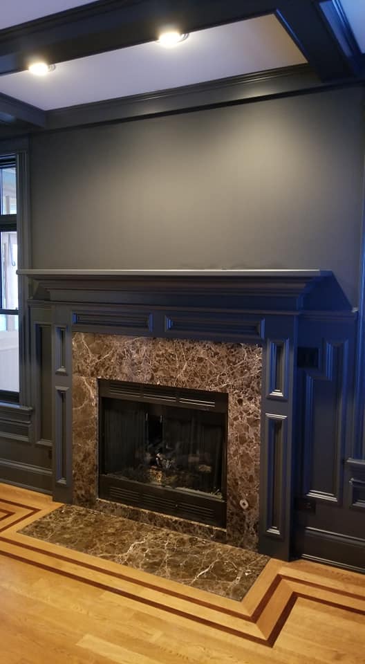 A fireplace with marble tile and blue walls.