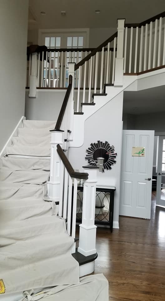 A staircase with white carpeting and black railing.