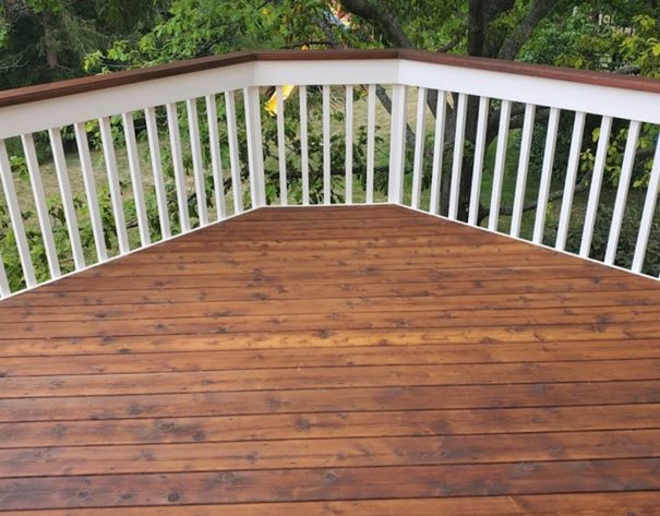 A deck with wood stain and white railing.