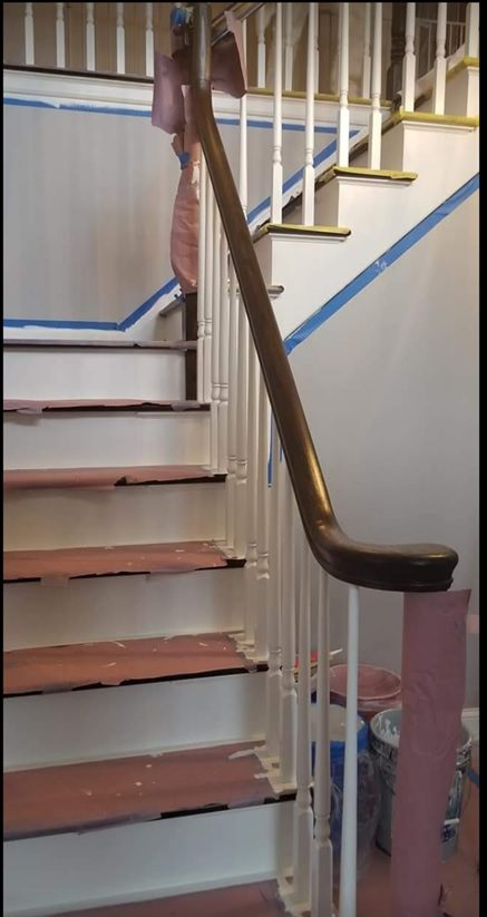 A wooden handrail on the bottom of stairs.