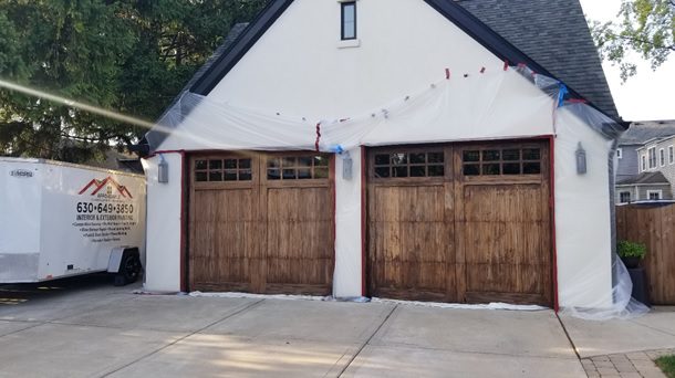 A couple of wooden garage doors in front of a house.
