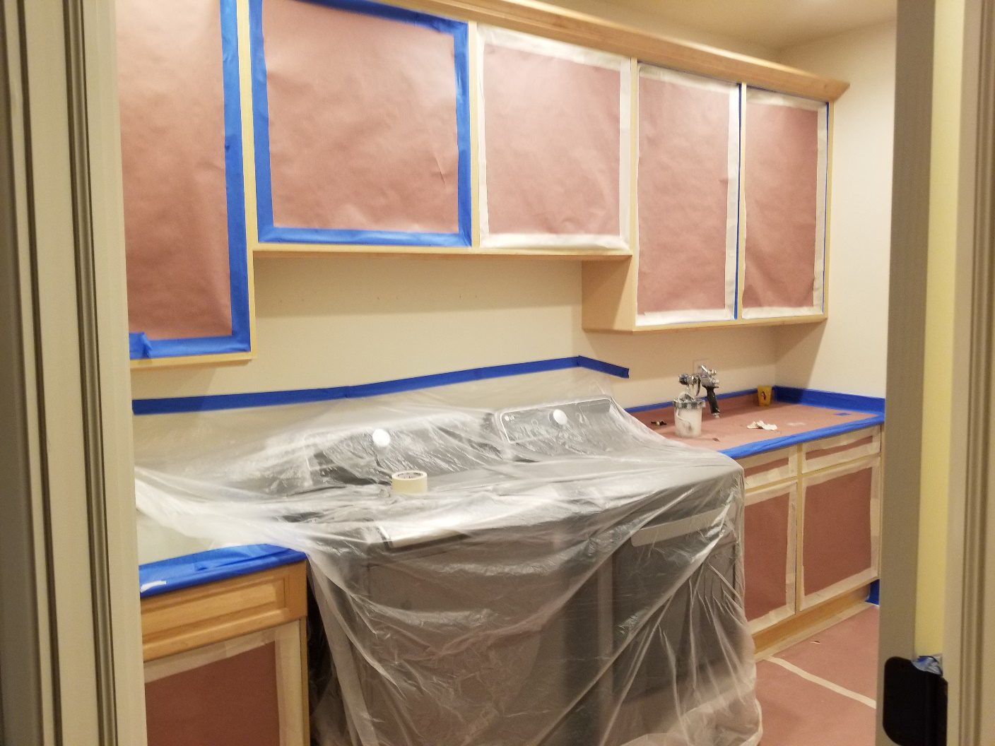 A kitchen with cabinets and appliances covered in plastic.