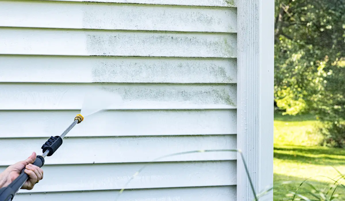 Power washing technician cleaning mold and debris from white vinyl siding to prepare for exterior paint application on a residential home in Barrington South.