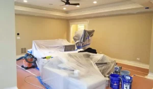 Professional prep work before repaint your home interior project in Downers Grove, showing plastic-covered furniture, Sherwin-Williams supplies, and clean masking setup.
