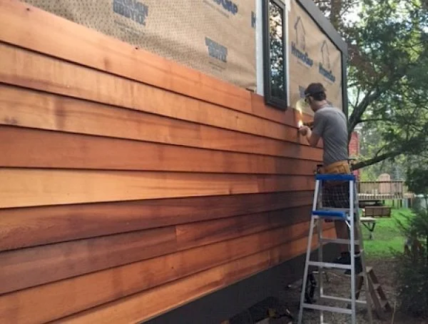 Professional contractor installing horizontal cedar wood siding on a residential home exterior, showcasing custom cedar siding installation and exterior remodeling craftsmanship.